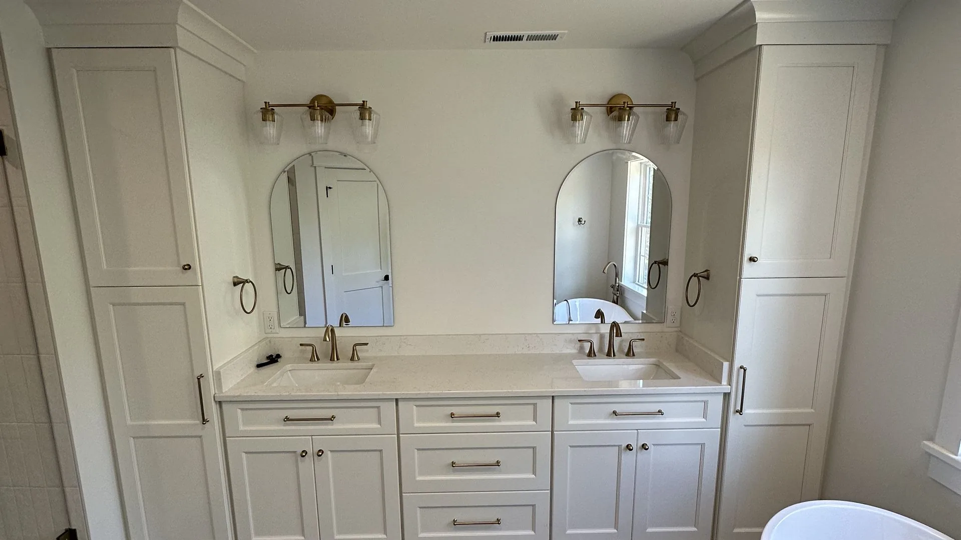 Remodeled primary bathroom with double vanity, arched mirrors, and freestanding tub. Addison Creek, Richmond, VA